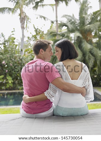 Rear view of an affectionate young couple sitting at the garden