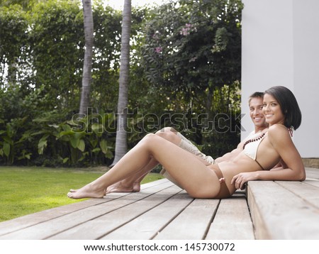 Full length side view of a semi dressed young couple relaxing outdoors