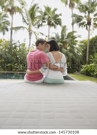 Rear view of an affectionate young couple sitting at the garden