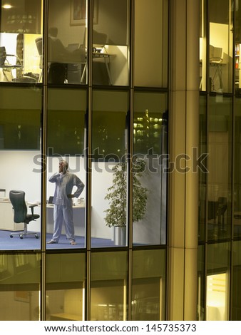 Full length of middle aged businessman in nightwear yawning at office