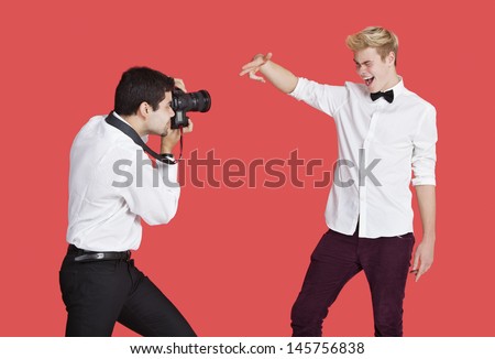 Male actor being photographed by paparazzi over red background