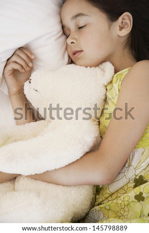Closeup of girl with teddy bear sleeping in bed