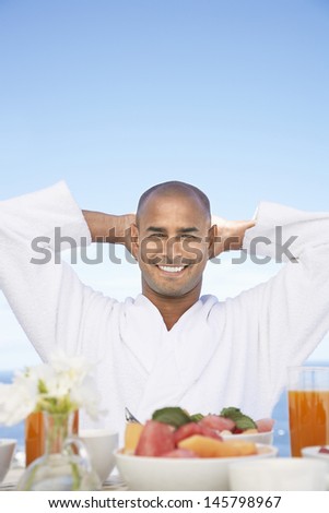 Portrait of happy African American man in bathrobe sitting at breakfast table