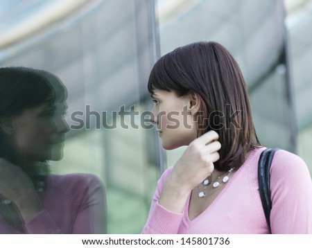 Young businesswoman looking at reflection of self in window