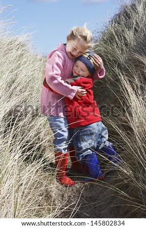 Full length of brother and sister embracing in long grass