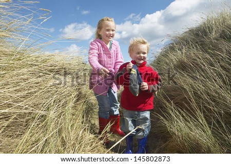 Full length of brother and sister standing among long grass