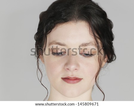 Closeup of beautiful young woman looking down on grey background