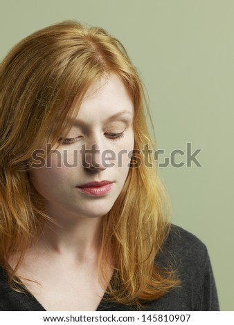 Closeup of unhappy young woman looking down on colored background