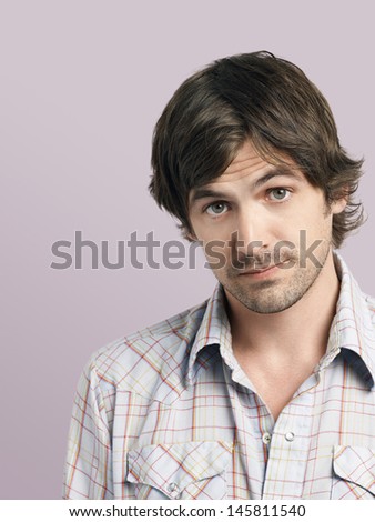 Closeup of confused young man raising eyebrows isolated on colored background