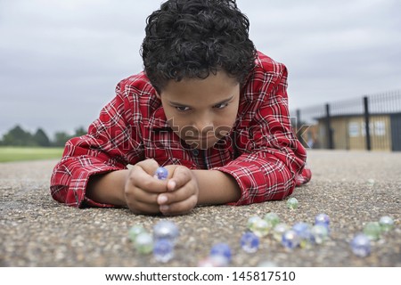 Closeup of young boy playing marbles on playground
