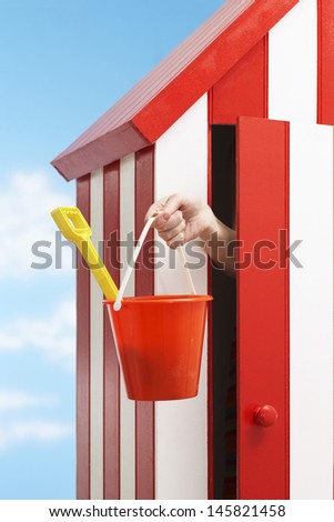 Woman\'s hand holding bucket and spade in beach cabin