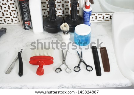 Scissors; combs; razor and brush on counter in barber shop