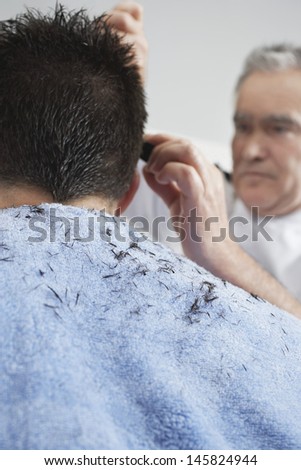 Closeup of male hairdresser cutting man\'s hair in barber shop