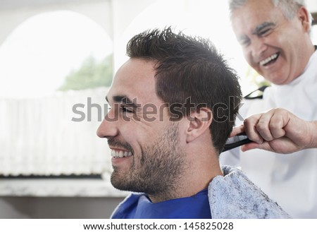 Closeup Of Happy Man Getting An Haircut From Barber In Hair Salon