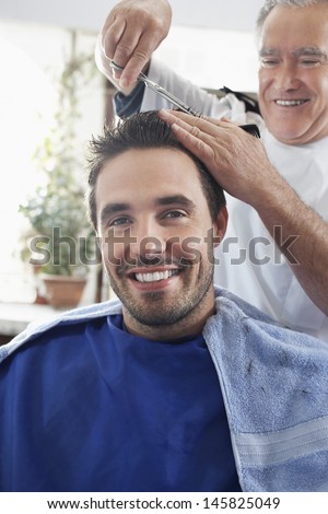 Portrait of happy man getting an haircut from hairdresser in barber shop