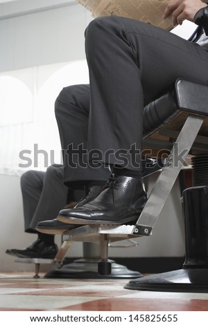 Low section of businessmen waiting for haircut in hair salon