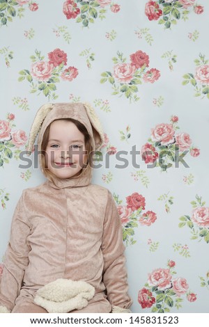 Portrait of a cute young girl in bunny costume against wallpaper with floral pattern