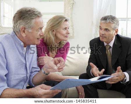 Mature Couple Sitting On Sofa With Financial Advisor