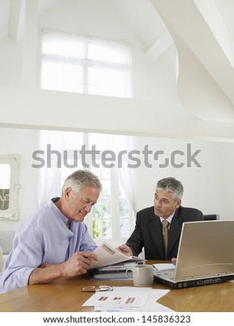 Mature man sitting at table with financial advisor