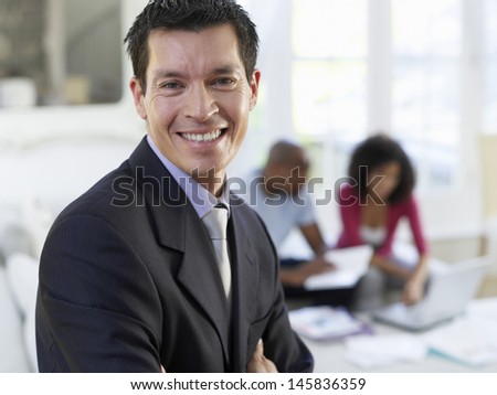 Closeup portrait of a financial consultant with arms crossed and couple sitting in background