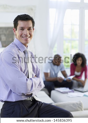 Portrait of a financial consultant with arms crossed and couple sitting in background