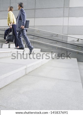 Side view of two business people walking up steps outdoors