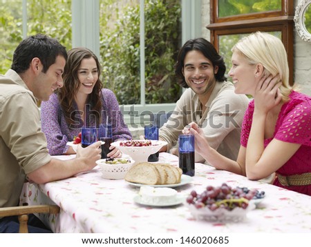 Group of four young people sitting at verandah table