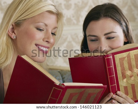 Closeup of two cheerful young women with books