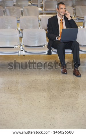 Businessman using mobile phone and laptop in the airport lobby