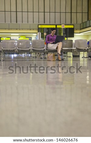 Young businesswoman using laptop in the airport lobby