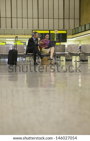 Businessman and woman using laptop in the airport lobby