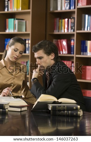 Young man and woman studying at desk in the library