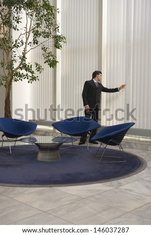 Full length of a young businessman looking out of window in office lobby