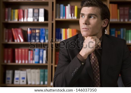 Thoughtful young man in formals in the library