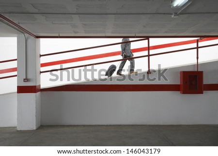 Side view low section of a businessman walking up ramp in parking garage with luggage