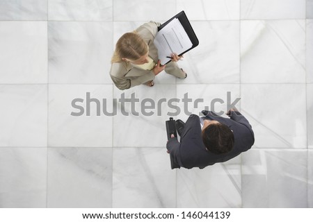 Top view of a businessman and woman conversing in office lobby