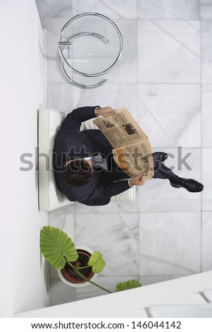 Top view of a young businessman reading newspaper in the office lobby