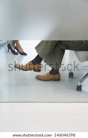 Side view lowsection of two office workers sitting in office