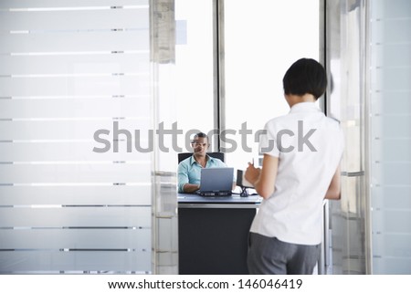 Smiling young man talking to woman standing in doorway at his office