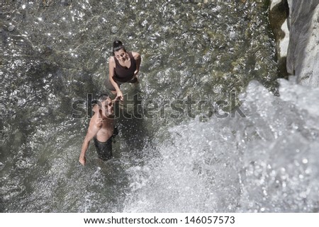 Top view of a happy couple holding hands under waterfall