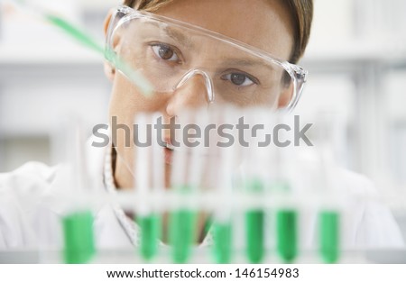 Closeup of a female scientist filling test tubes with pipette in laboratory