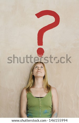 Young blond woman leaning against wall with painted question mark over head