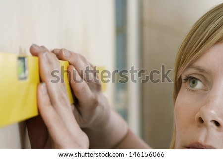 Extreme closeup of a blond young woman using spirit level