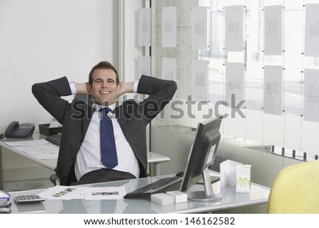 Portrait of a relaxed young businessman sitting at desk in office
