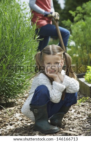 Portrait of a little girl in garden with midsection of mother