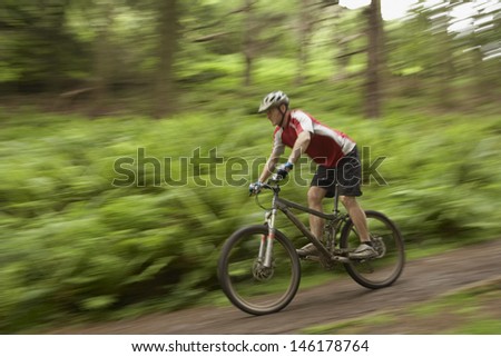 Side view of a blurred male cyclist on countryside track