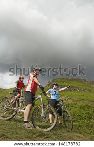 Low angle view of three cyclists against the hill