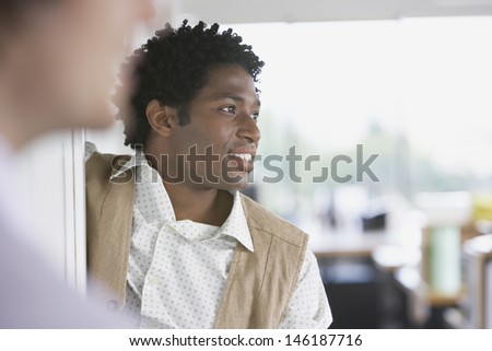 Smiling African American businessman with colleague looking away in office