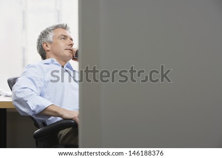 View through door of a middle aged businessman using phone in office