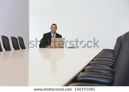 Middle aged businessman with laptop in board room